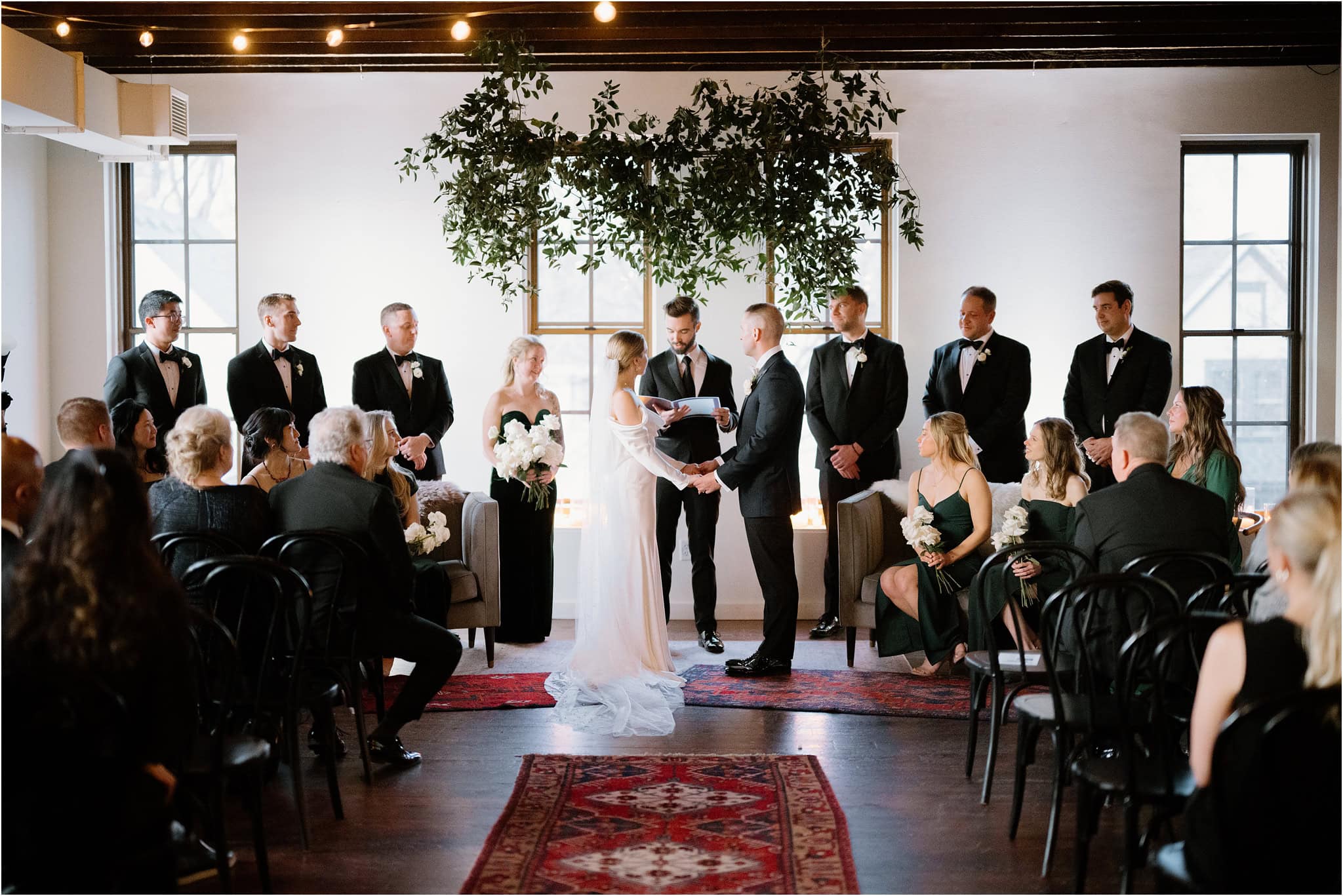 Cozy Wedding ceremony inside with the bride and groom standing in the center surrounded by their wedding party